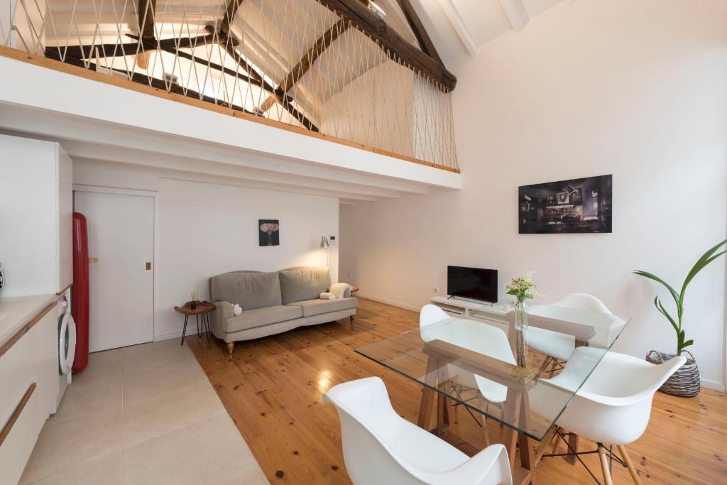ein Wohnzimmer mit einem Glastisch und weißen Stühlen in der Unterkunft Art Mezannine with Garden in Porto