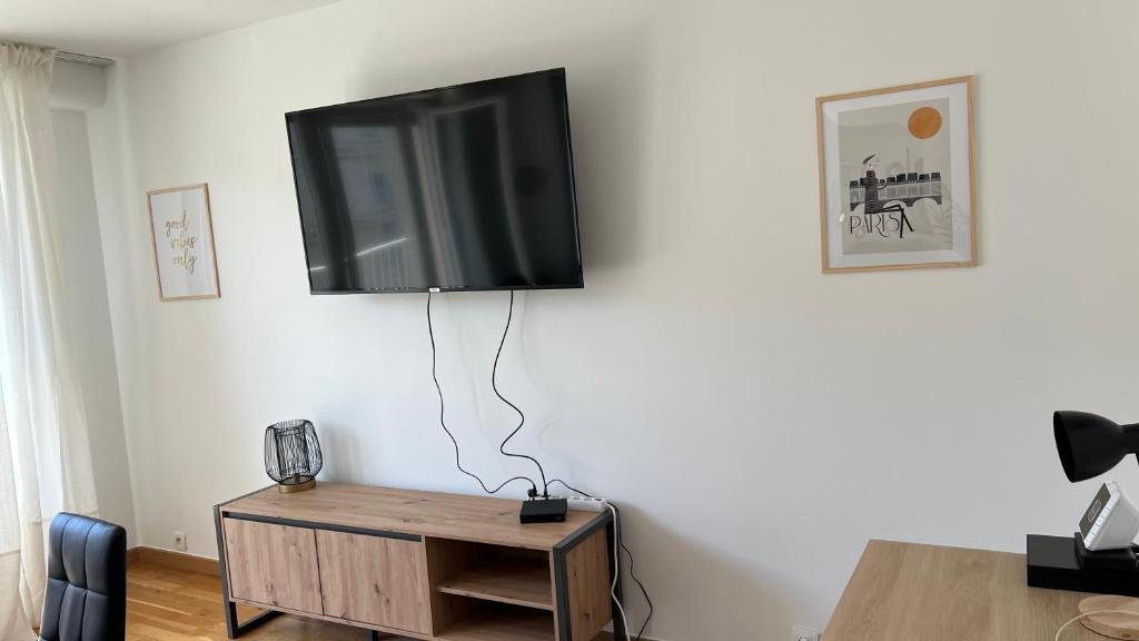 TV de pantalla plana colgada en una pared blanca en Superbe appartement en centre-ville, 20min de Paris, 5 min d&#39;Enghien, en Saint-Gratien