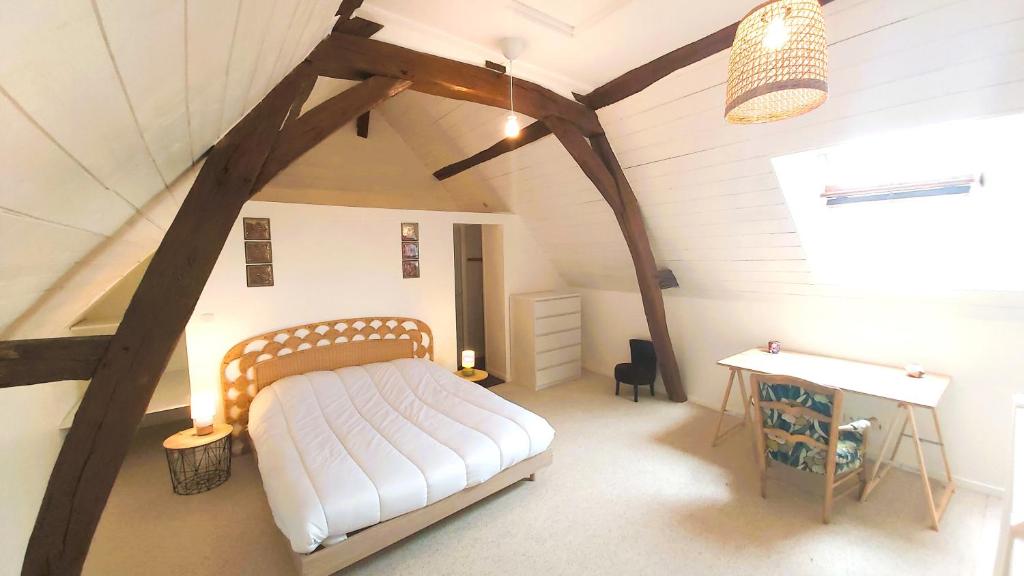 a bedroom with a bed and a desk in a attic at La Maison de Louise Chinon #chateaux #vignobles in Chinon
