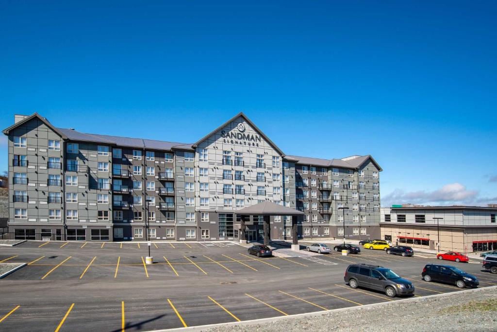 un grand bâtiment avec des voitures garées dans un parking dans l'établissement Sandman Signature St. John's Hotel, à Saint-Jean