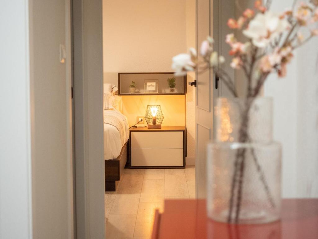 Un dormitorio con una cama y una mesa con un jarrón de flores en Apartamento PLAYA12, en Gijón