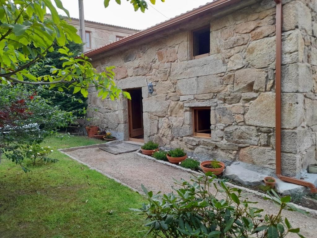 un edificio de piedra con macetas delante de él en A Casa da Gombra, en Villanueva de Arosa