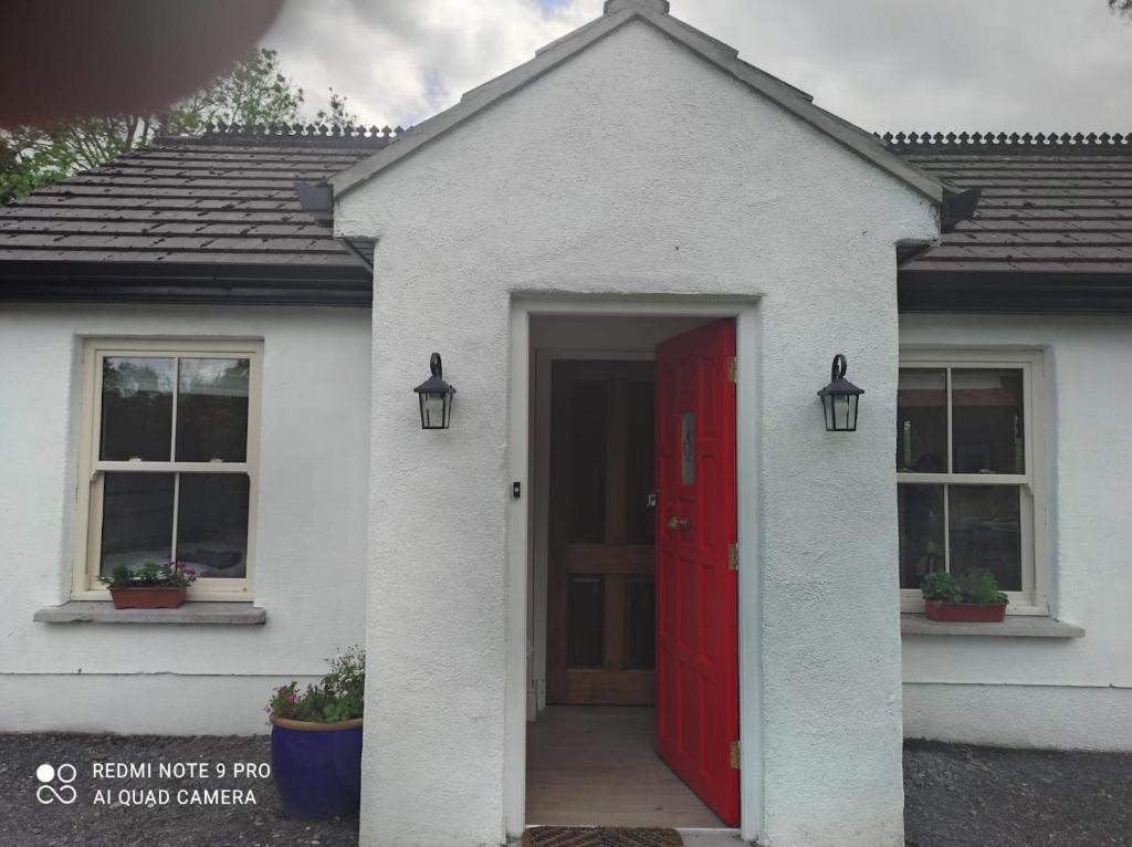 a white house with a red door and two windows at The Wild Farm Lodge in Mullingar