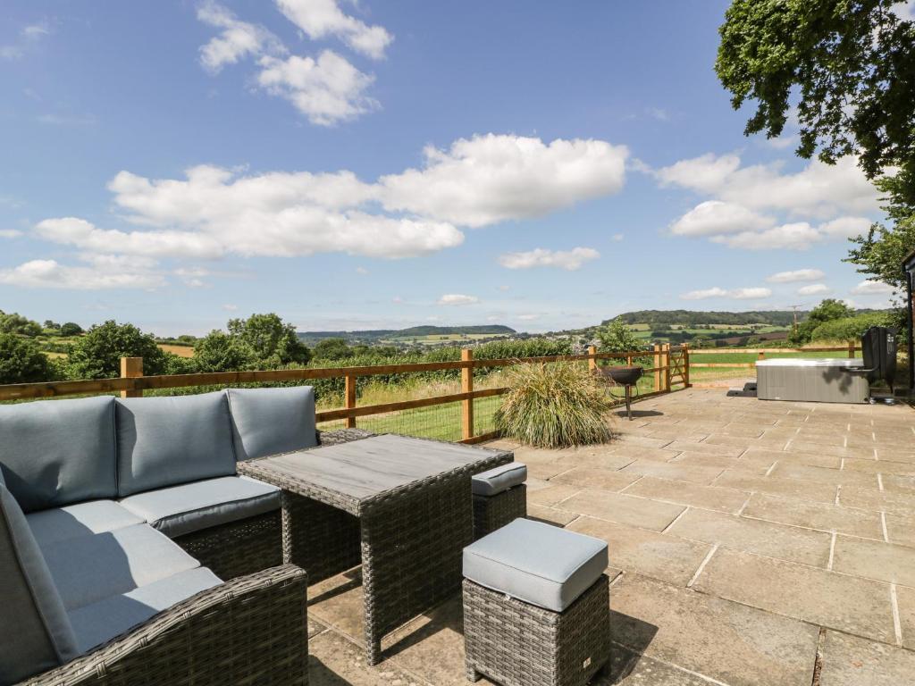 a patio with a couch and a table with a view at The Old Kennels in Sidmouth