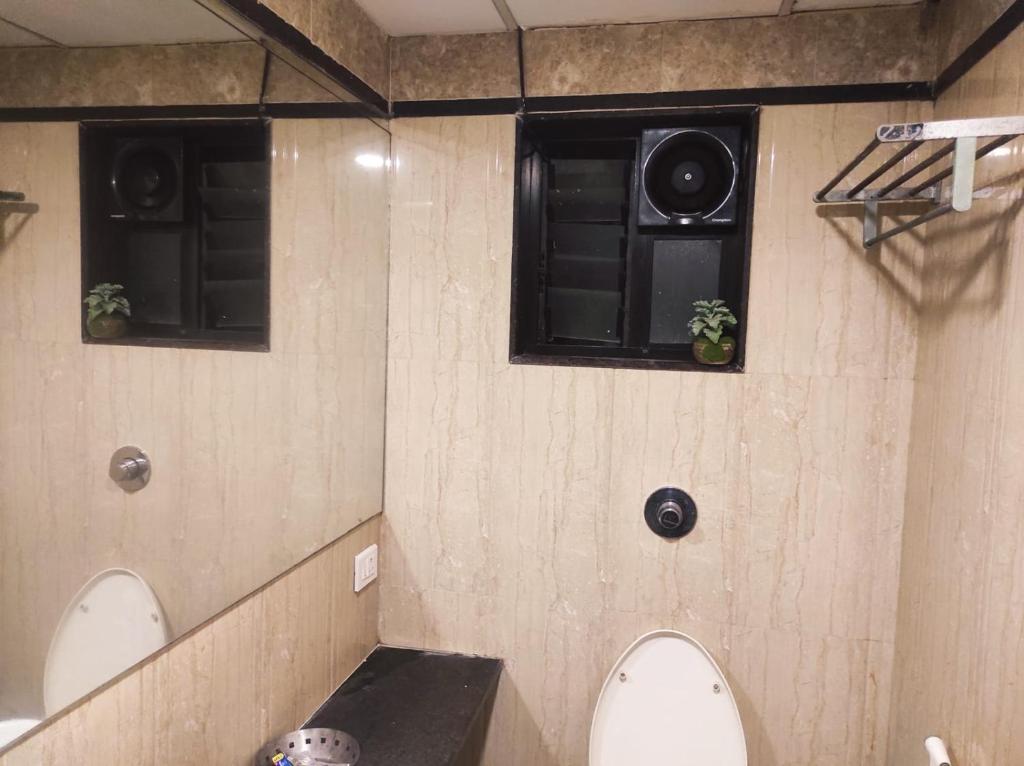 een badkamer met twee luidsprekers aan de muur en twee toiletten bij Hotel Vaishnavi in Solapur