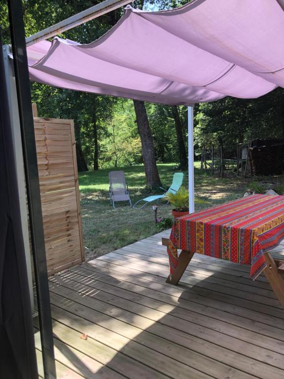 una mesa de picnic bajo un paraguas púrpura en una cubierta en Chez Marie et Jean nature calme terrasse parking en Pujols-sur-Ciron