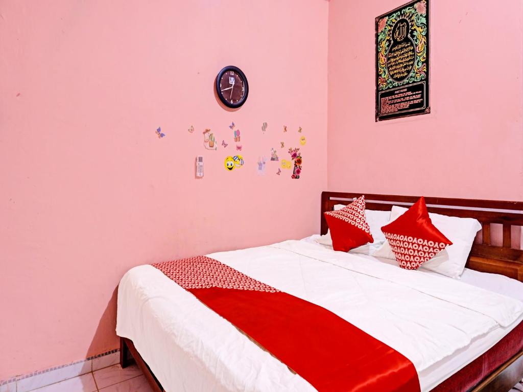 Schlafzimmer mit einem Bett mit roter und weißer Bettwäsche in der Unterkunft OYO 91428 Duta Stay in Tanjung Pinang 