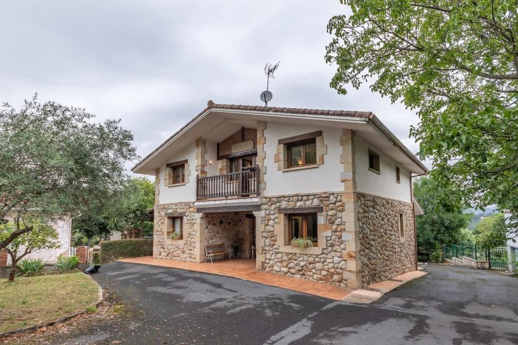 a large stone house with a balcony on a street at Caserío entre Bilbao y Urdaibai in Morga