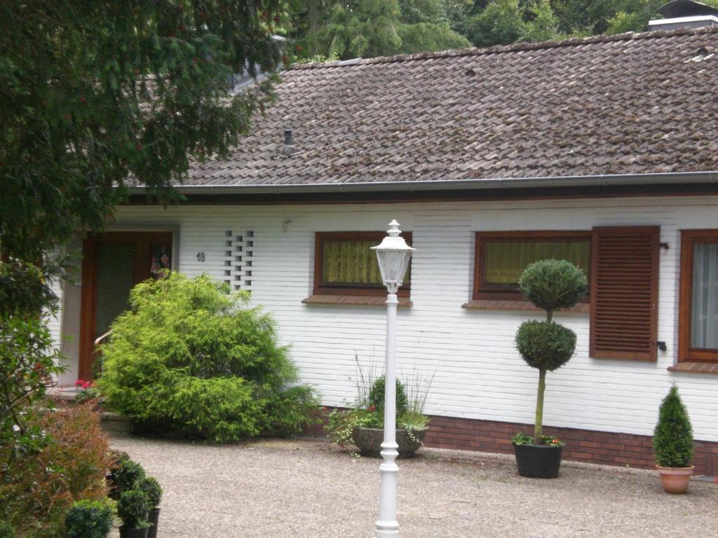een wit huis met een straatlicht ervoor bij Ferienwohnung Heidis Heidehaus in Schneverdingen