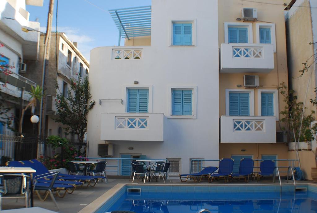 un hotel con piscina, sillas y un edificio en Super economy studio en Agia Pelagia