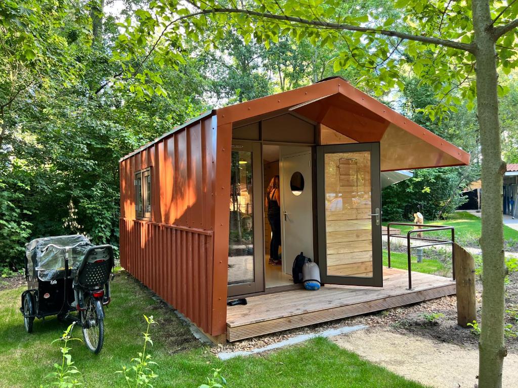 a tiny house in the grass next to a bike at Camping Vliegenbos in Amsterdam