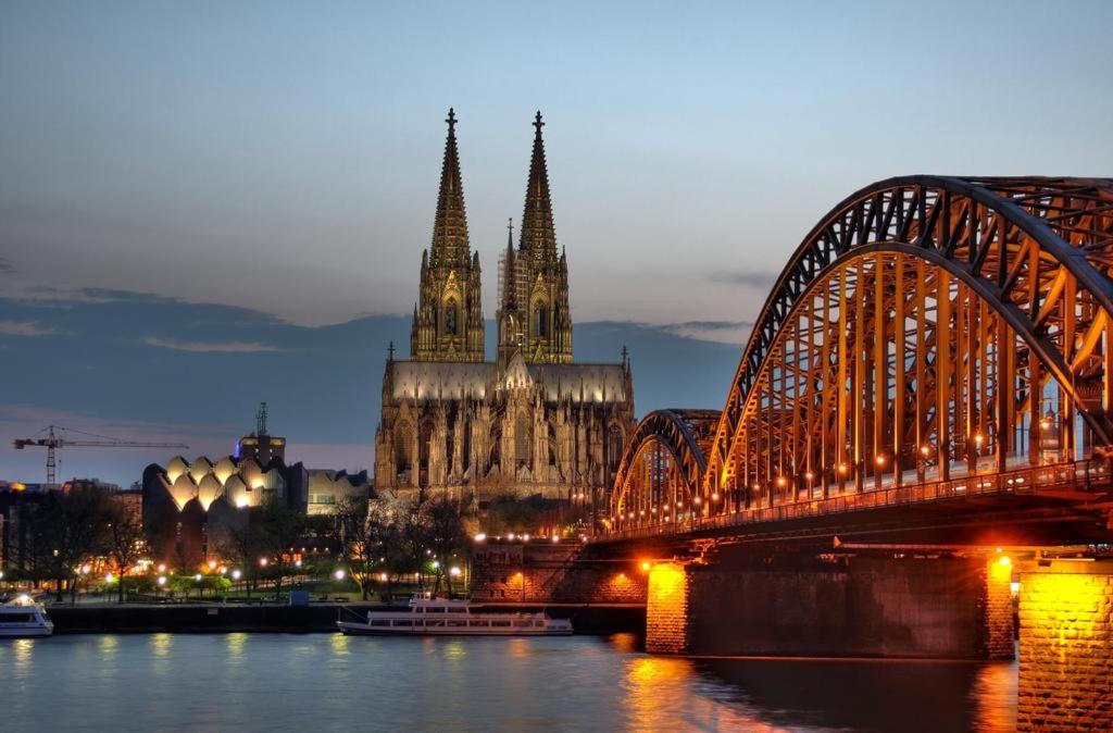 uma ponte sobre um rio ao lado de uma catedral em FeWo Central em Colônia