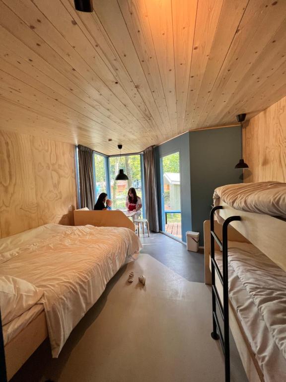 sypialnia z 2 łóżkami i kobieta siedząca na krześle w obiekcie Camping Vliegenbos w Amsterdamie