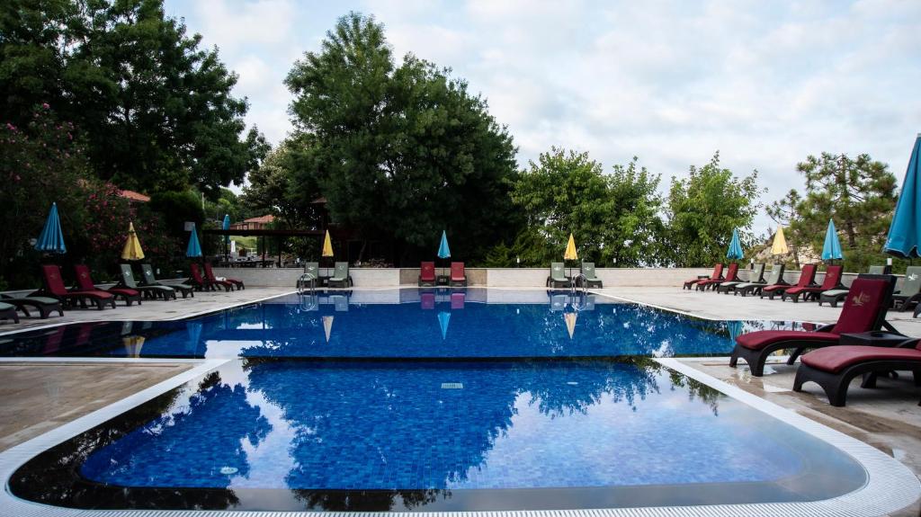 a pool at a resort with chairs and umbrellas at Fener Motel in Şile