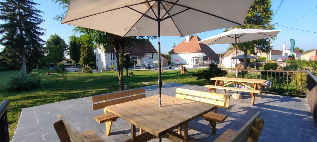 a picnic table with an umbrella and two benches at Domaine Ravy-La Camélia in Saint-Symphorien-sur-Saône