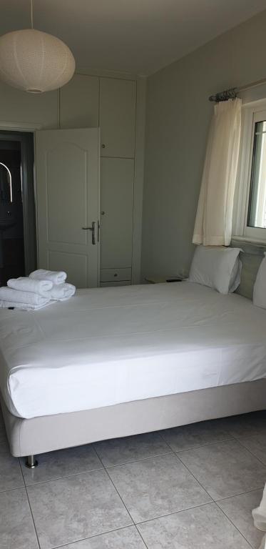duże białe łóżko z ręcznikami w pokoju w obiekcie Beachfront Houses w mieście Pogoniá