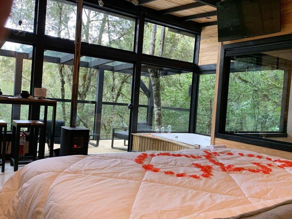 a bedroom with a large bed with red flowers on it at Floresta Secreta- Pousada Cachoeira da Neve in Urubici