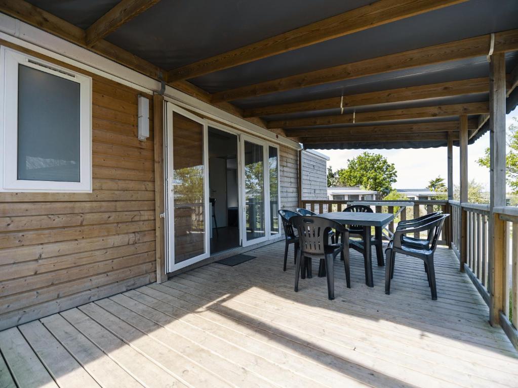 a wooden deck with a table and chairs on it at Camping Paradis 4 étoiles Au Port de L'Houmeau - La Rochelle in LʼHoumeau