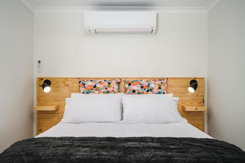 a bedroom with a bed with a wooden headboard at Church Lane Accommodation, Milawa. in Milawa