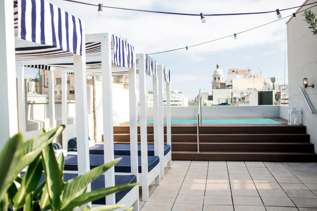 einen Balkon mit blau und weiß gestreiften Stühlen und Treppen in der Unterkunft Hotel Midmost by Majestic Hotel Group in Barcelona