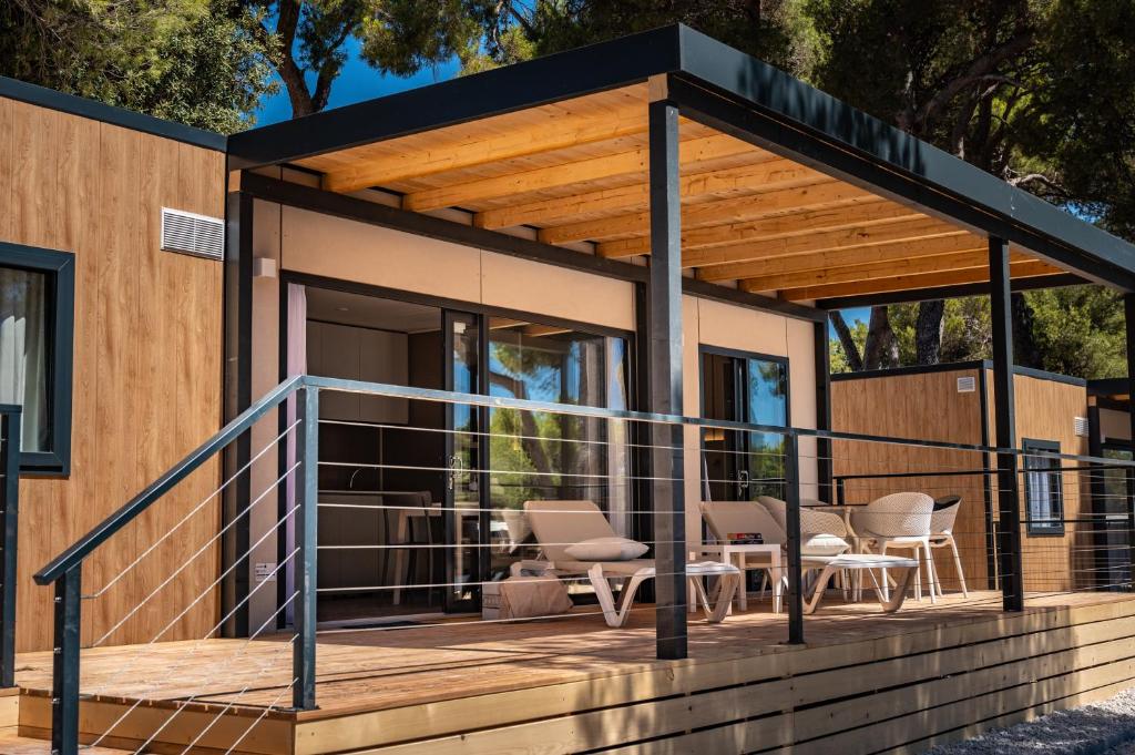 a tiny house with a large deck with chairs at Arena Stoja Camping Homes in Pula