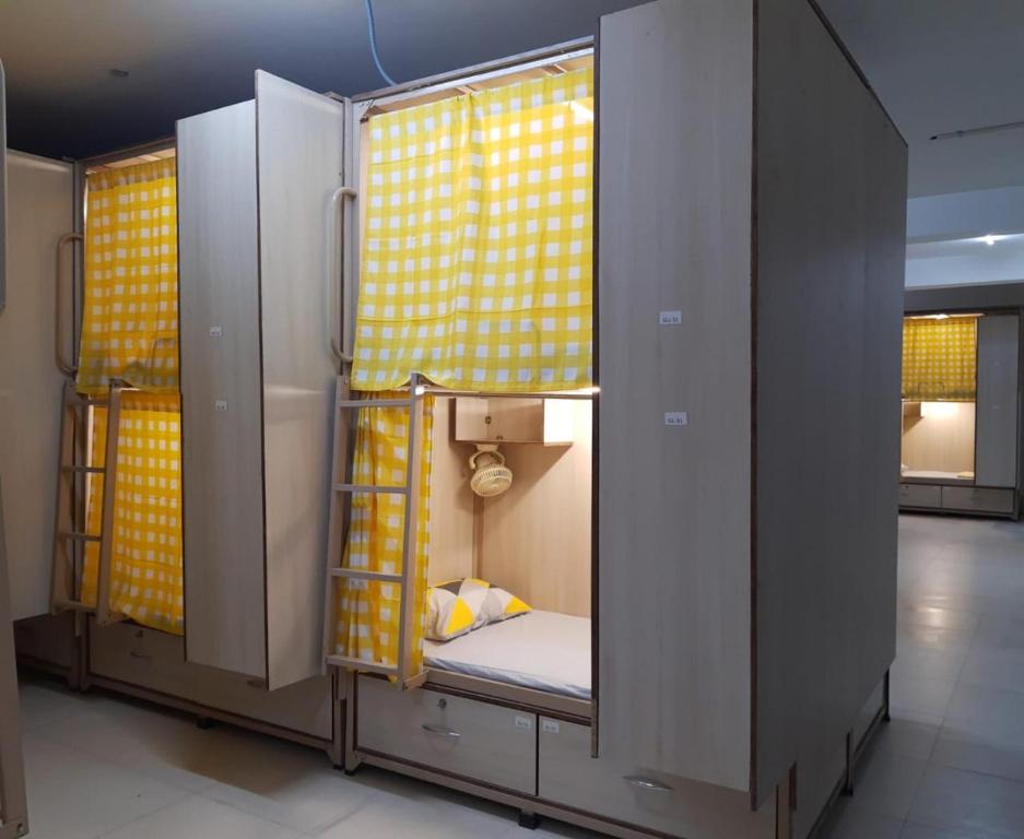 a small room with a bunk bed with yellow curtains at Abuzz OxfordCaps, Genome Valley Hyderabad in Hyderabad