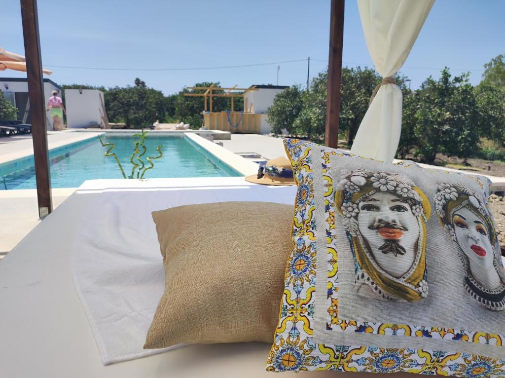 a pillow sitting on a bed next to a pool at AgriBarocco in Noto