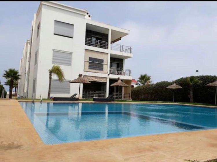 a building with a swimming pool in front of a building at Appartement front de mer avec piscine à Dar Bouazza in Dar Bouazza