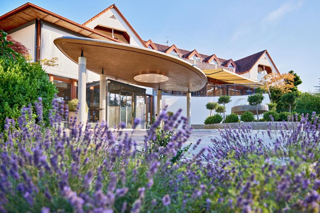 dom z fioletowymi kwiatami przed nim w obiekcie Ayurveda Resort MANDIRA w mieście Bad Waltersdorf