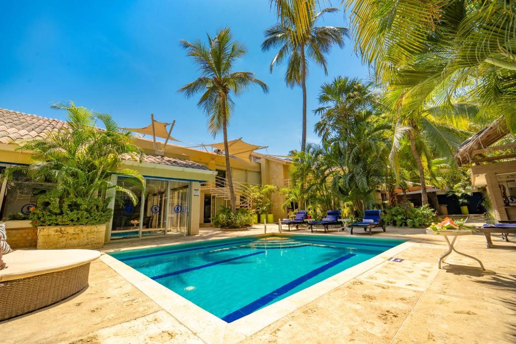 a swimming pool in front of a house with palm trees at Santorini Hotel Boutique in Santa Marta