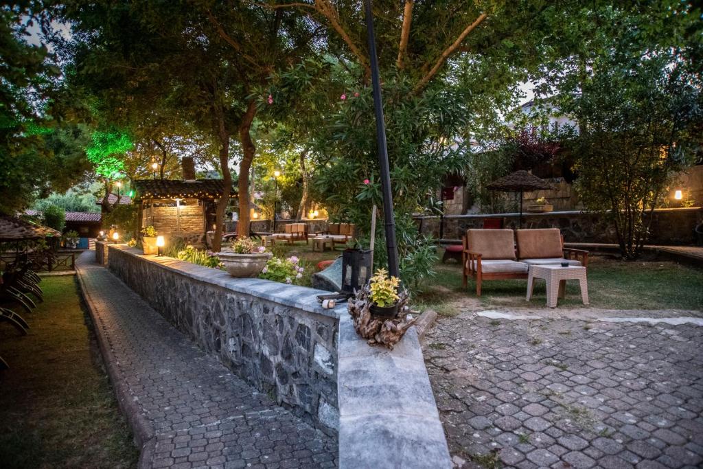 a garden at night with a stone wall and trees at Fener Motel in Şile