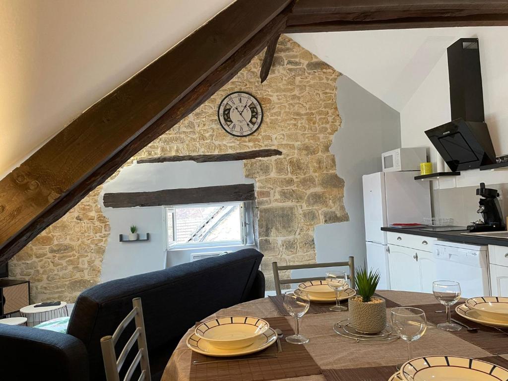 サルラ・ラ・カネダにあるAppartement* authentique meublé Sarlat coeur villeのダイニングルーム(テーブル、壁掛け時計付)