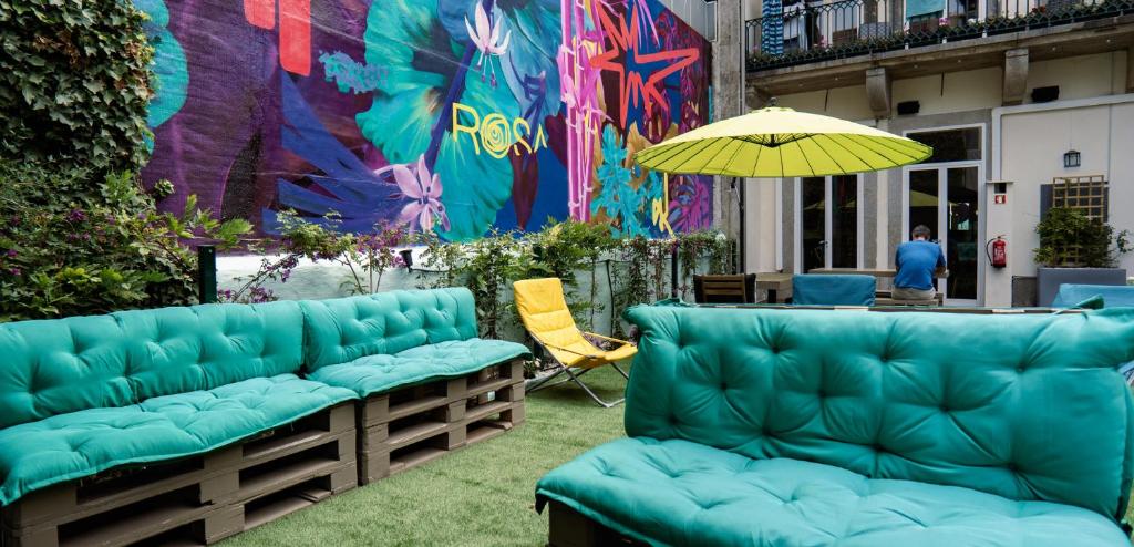 a patio with green couches and a table and an umbrella at Rosalma Hostel in Porto