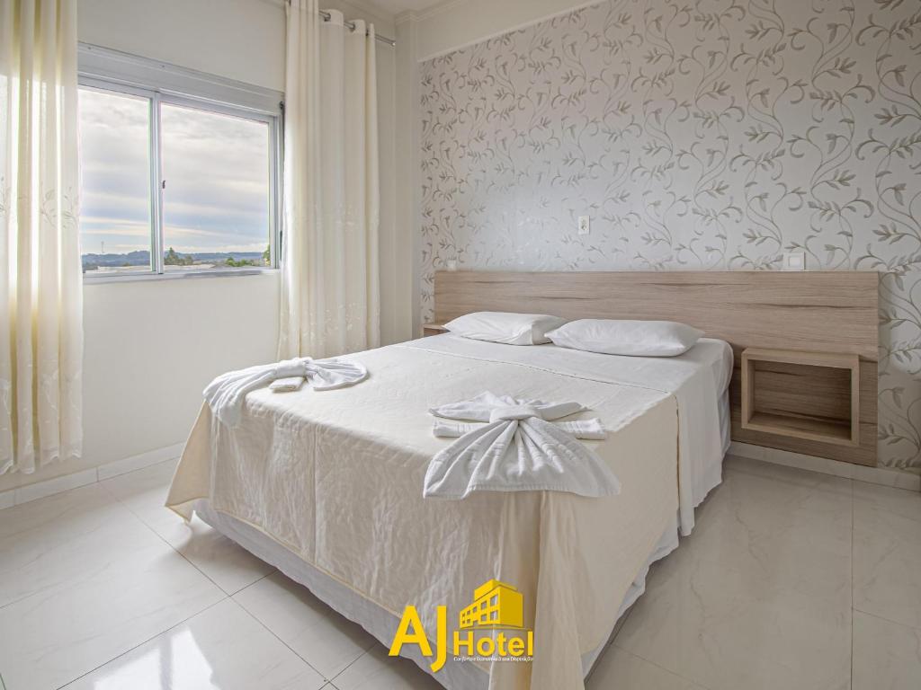 a bedroom with a white bed with a bow on it at AJ Hotel Chapecó - Fácil Acesso Pátio Shopping e Rótula da Bandeira in Chapecó