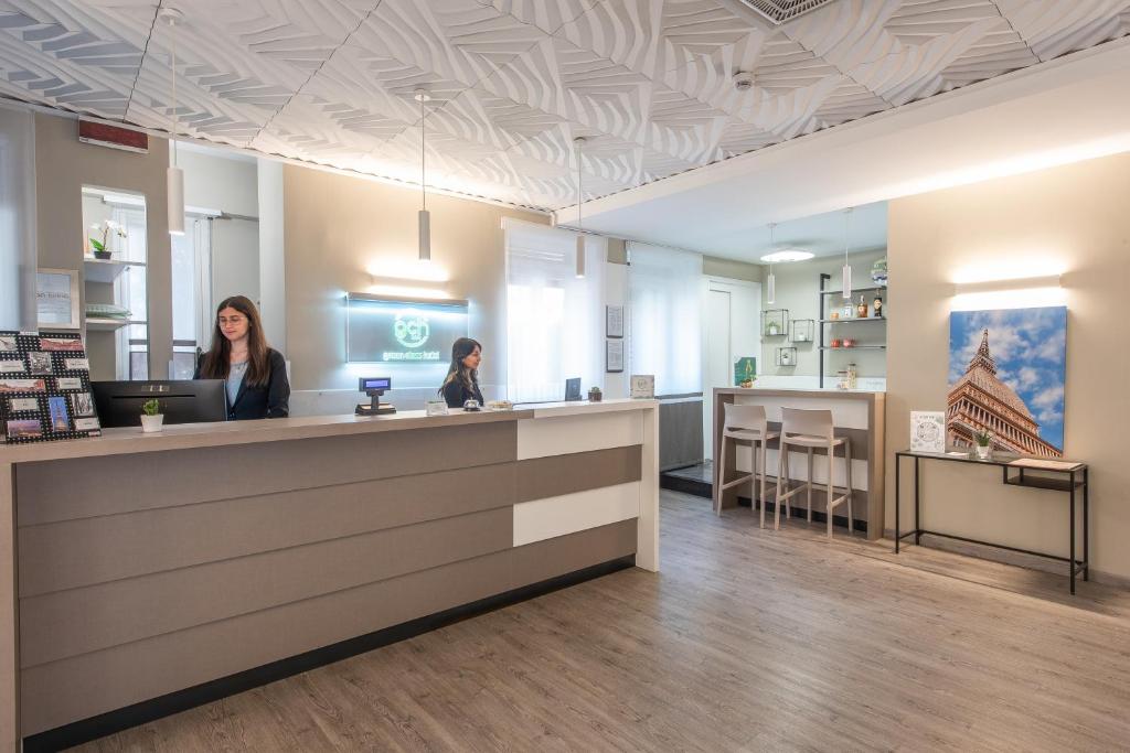 Dos mujeres sentadas en un mostrador en una tienda en Green Class Hotel Gran Torino, en Turín