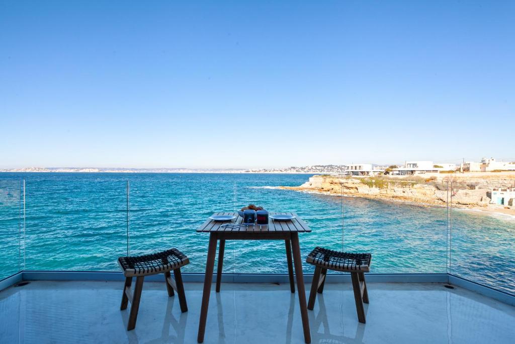 - une table et deux chaises sur un balcon donnant sur l'eau dans l'établissement CASA UMI - Magnifique appartement avec accès privé à la mer et grande terrasse, à Marseille