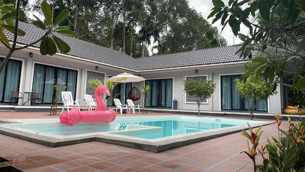 a swimming pool with a pink flamingo in front of a house at Pool Villa Nita in Ban Na Klang