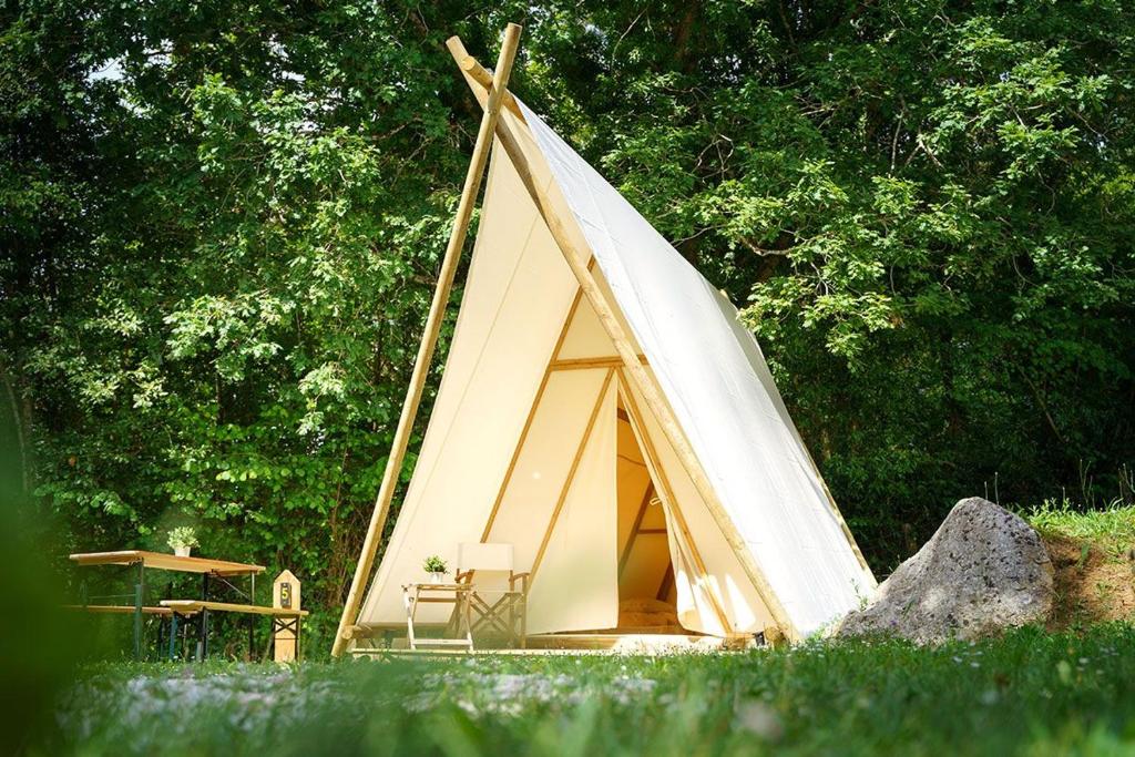a teepee tent with a chair in the grass at Kampaoh Cabañeros in Navas de Estena