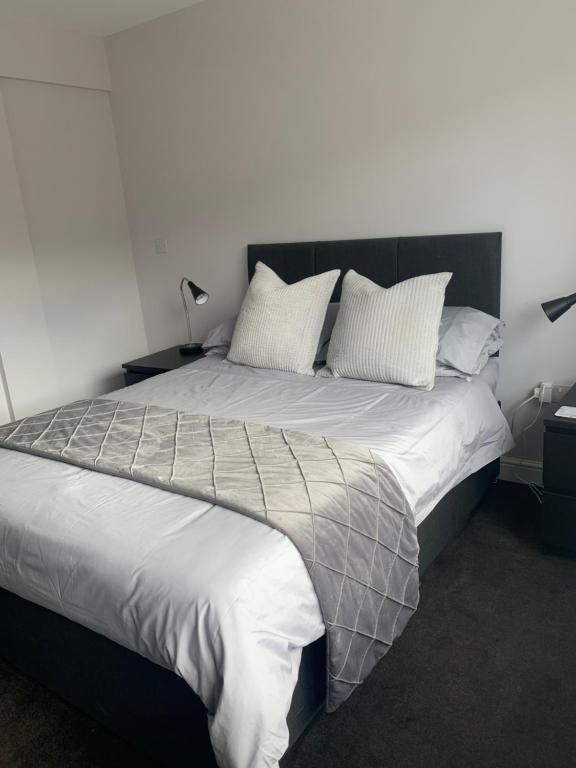 1 dormitorio con 1 cama grande con sábanas y almohadas blancas en Sutton Park Lodge en Sutton Coldfield