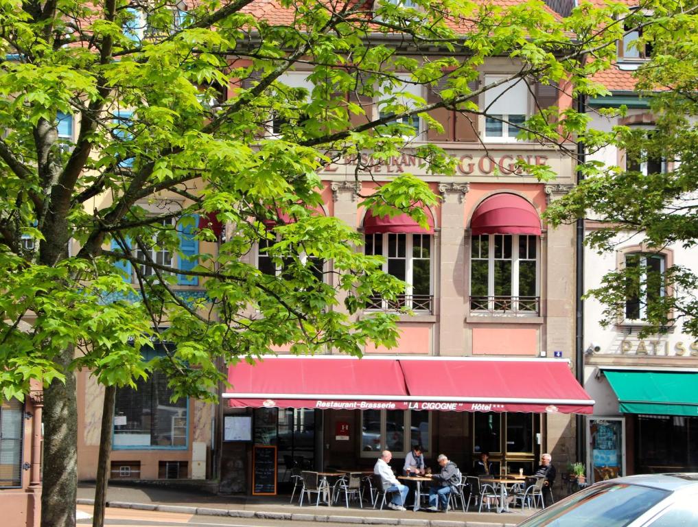 ein Restaurant mit einer roten Markise vor einem Gebäude in der Unterkunft Hôtel Restaurant La Cigogne in Munster