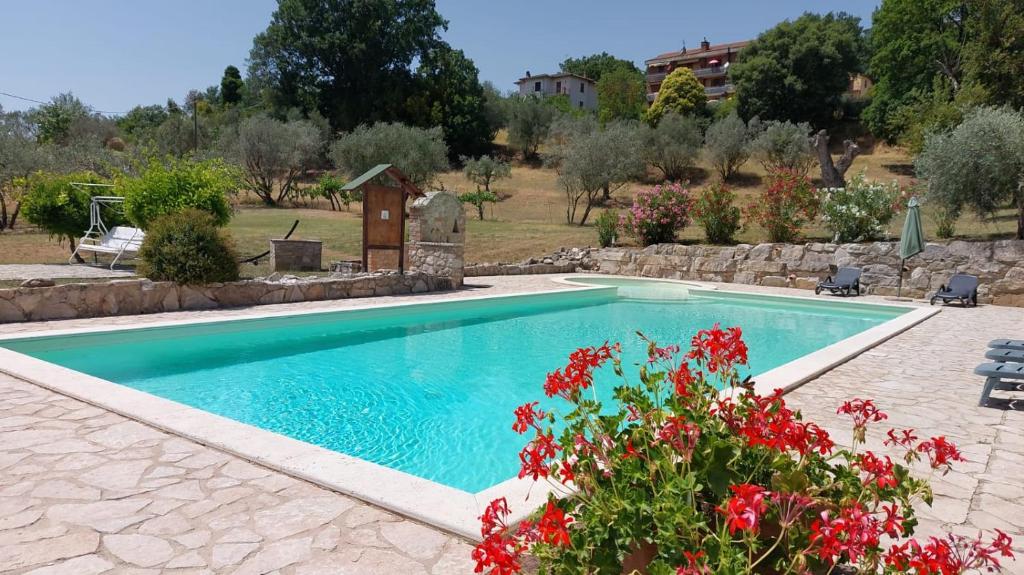 una piscina in un cortile con fiori rossi di Agriturismo Camera Rosa a Todi