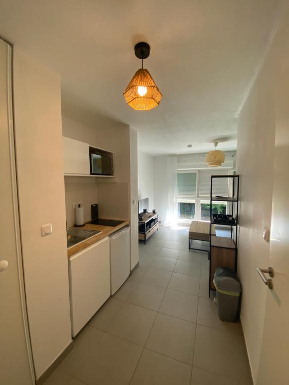 a kitchen with white cabinets and a light fixture at Studio rénové proche commodités in Pessac