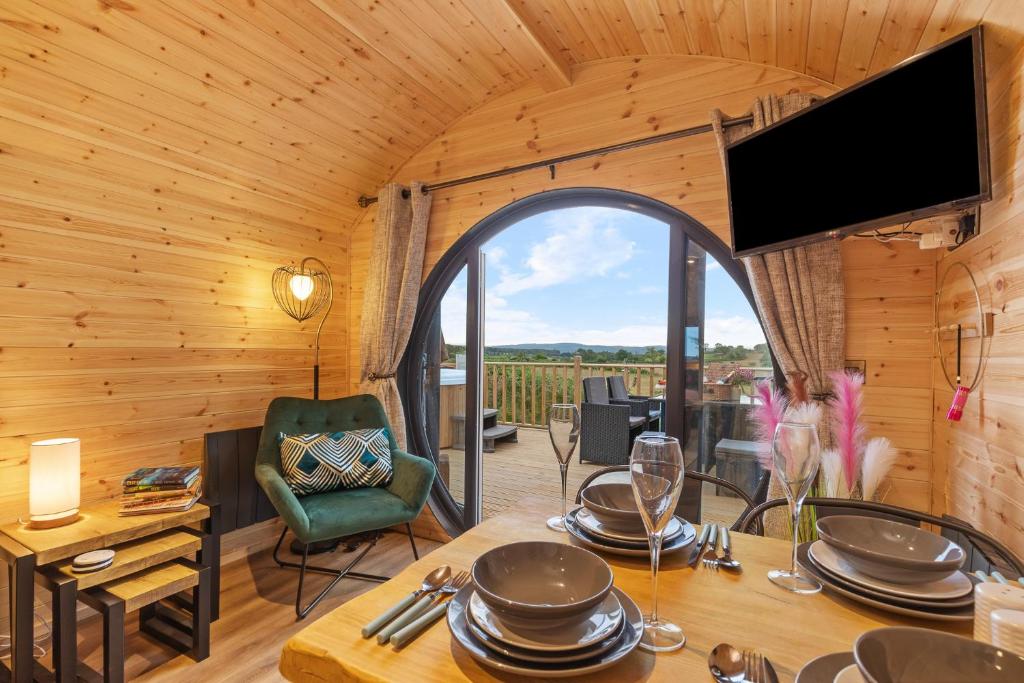 una sala da pranzo con tavolo e TV in camera di Blaenplwyf Luxury Countryside Shire Pods with Hot Tubs a Lampeter