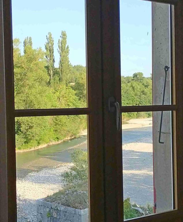 a window with a view of a river seen through it at -Moulin de Solaure- in Pont-de-Quart