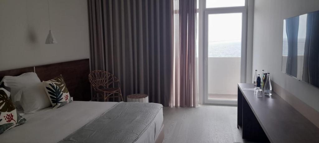 a bedroom with a bed and a large window at Porto Covo Praia Hotel & SPA in Porto Covo