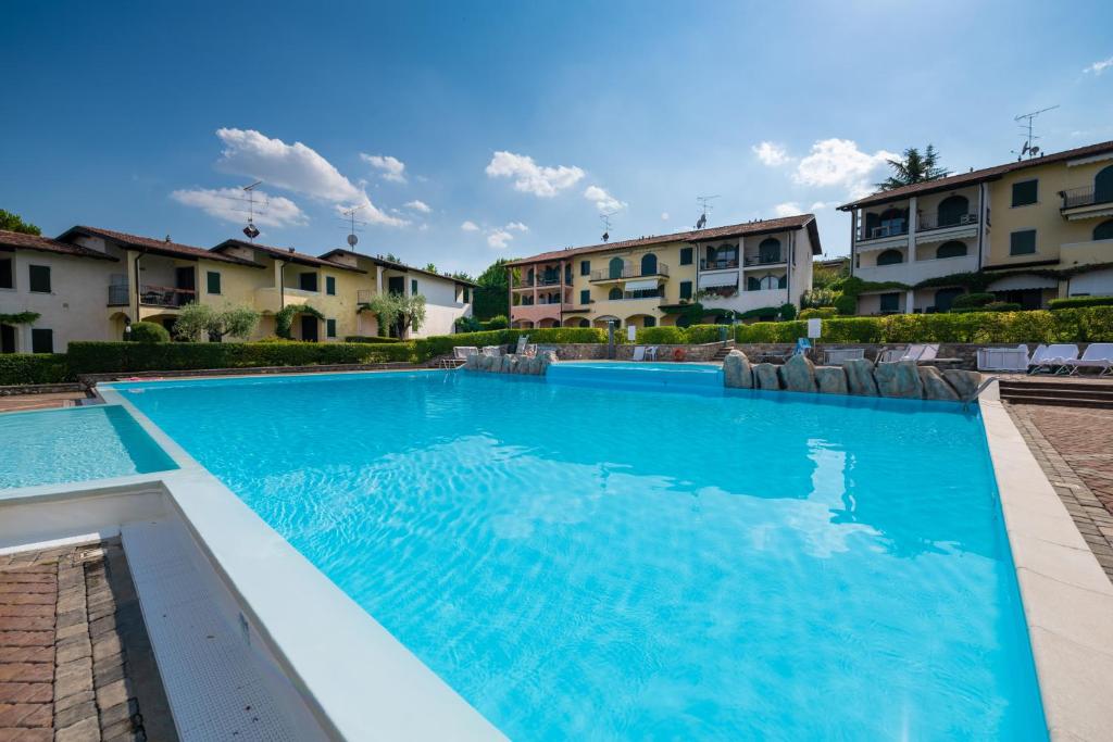 a large blue swimming pool with buildings in the background at Appartamento Katy in Polpenazze del Garda