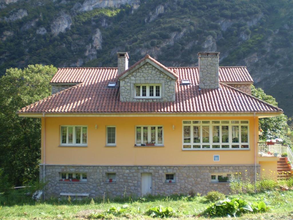 una casa amarilla con techo rojo en Hotel L'Ablana en Pola de Somiedo