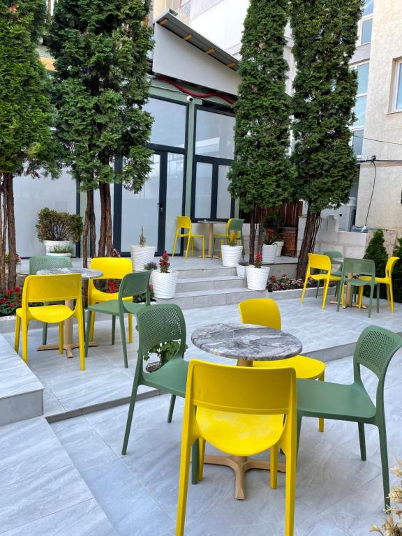 a patio with yellow and green tables and chairs at Hostel Dera in Pristina