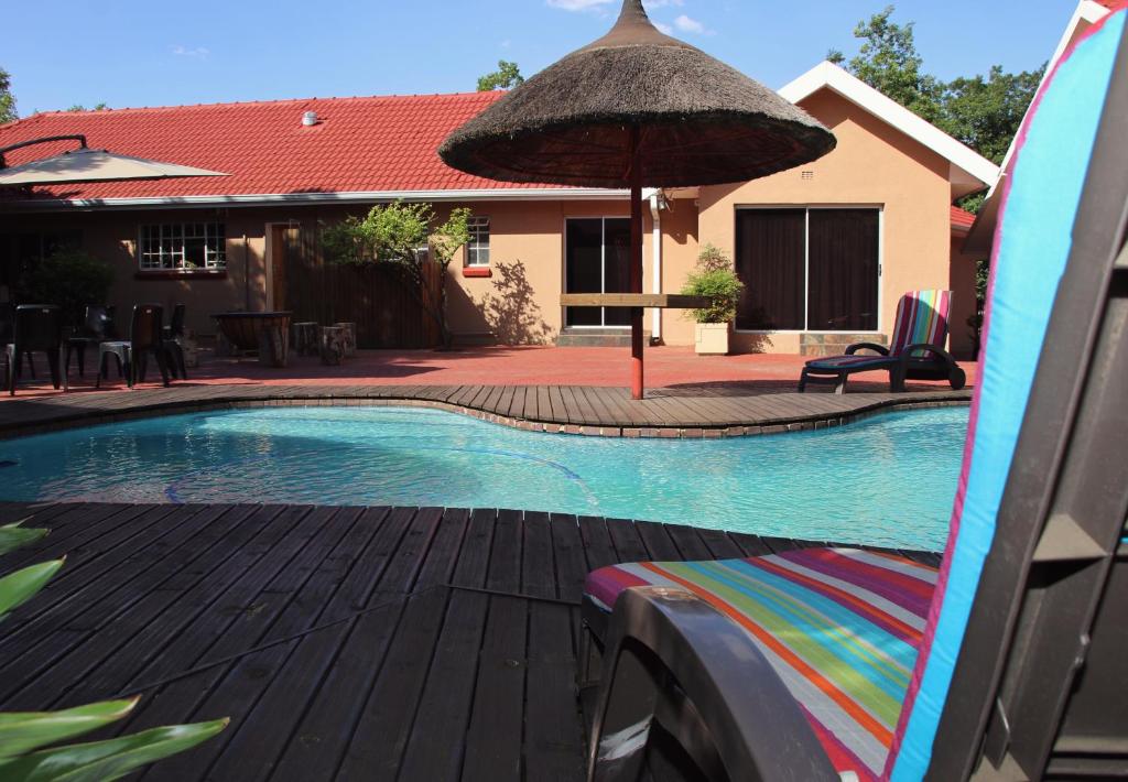 a swimming pool with a surfboard and an umbrella at Aalwyns Guesthouse in Vanderbijlpark