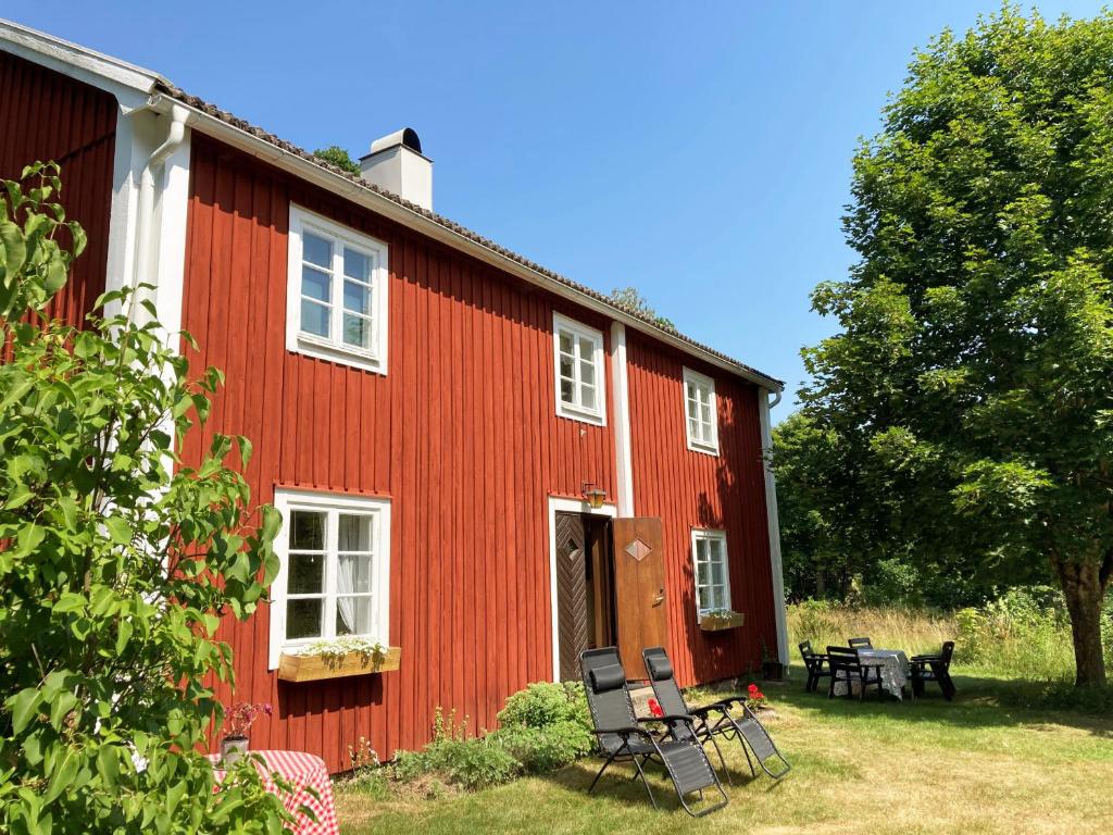 een rood huis met stoelen en tafels ervoor bij Nice holiday home with 100 meters to Lake Asnen in Ryd